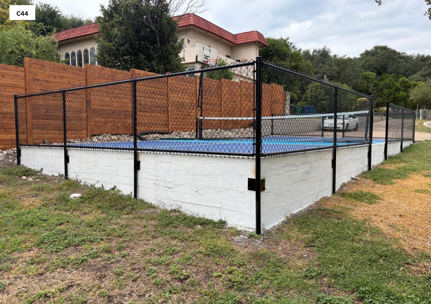 Black Vinyl Chain Link 4’ tall Black Vinyl Chain Link mounted to elevated Concrete wall with top & Bottom rails for tennis court